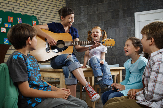 Music Teacher Playing Guitar for Class