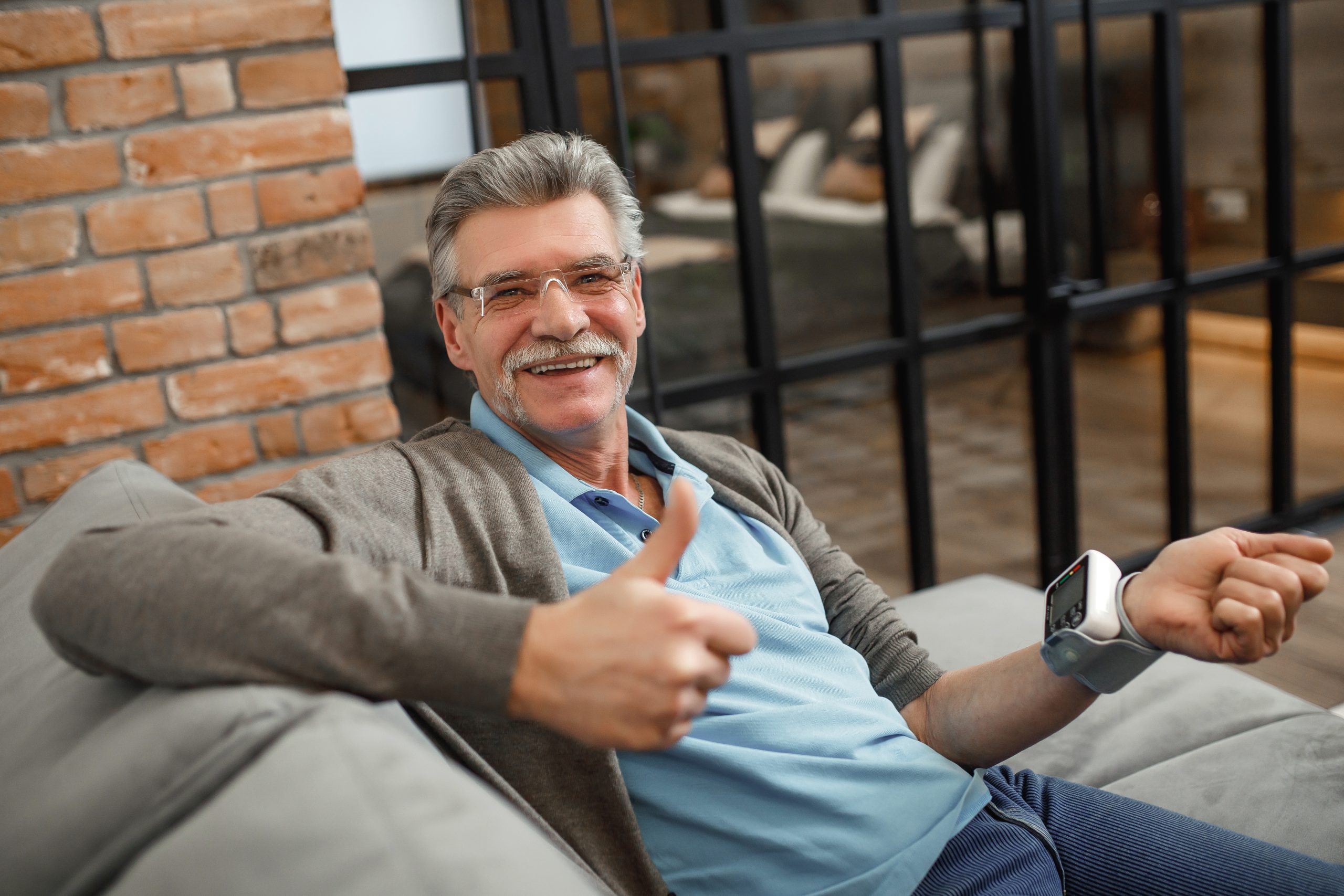 Senior man checking his blood pressure while lying at home sofa