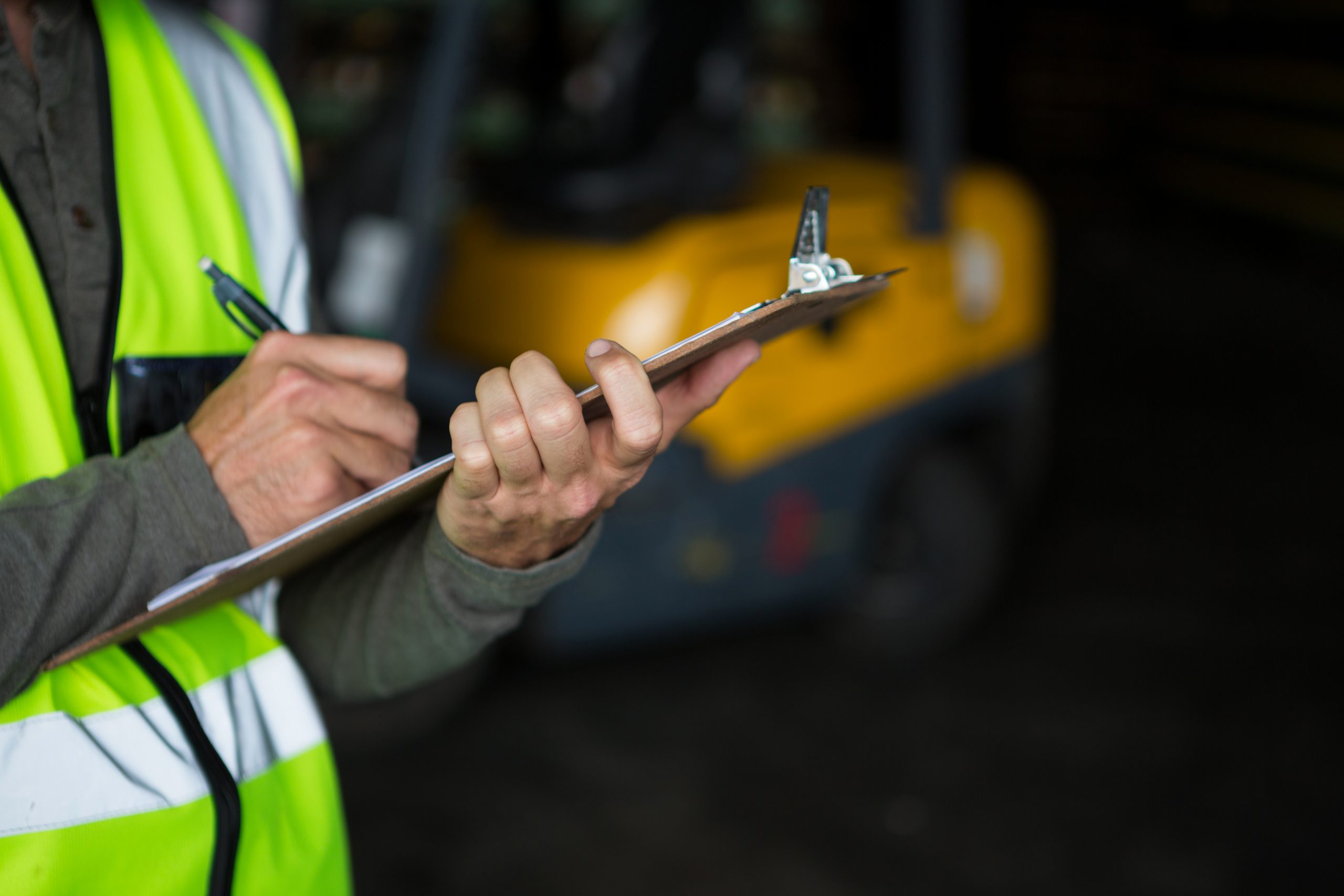 Male worker writing on clipboard in warehouse